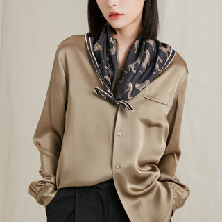 Elegant black silk scarf with gold leopard print pattern styled with a taupe silk blouse against neutral background, showcasing luxurious hand-rolled edges