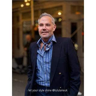 Navy blazer styled with dusty blue silk neckerchief elegantly knotted over striped shirt, showcasing the versatile wear of the paisley silk scarf