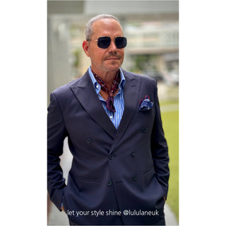 Navy suit paired with plum red paisley silk neckerchief and striped blue shirt, elegantly styled with matching pocket square