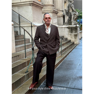 Men’s silk neckerchief featuring a beige horseshoe print, styled under the collar of a dark brown suit. The elegant silk scarf adds a refined touch to a dapper city look.