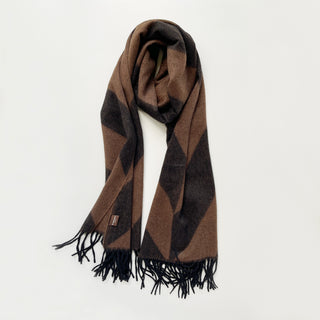 Brown and black herringbone cashmere scarf with fringed edges on light grey background.