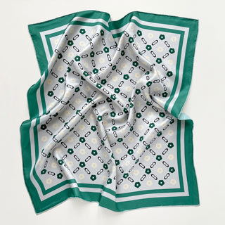 Square silk scarf with light grey center featuring teal green and cream floral pattern connected by chain links, bordered with elegant teal green trim