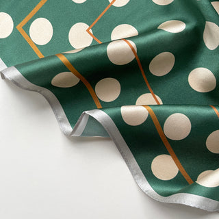 Jade green silk scarf with cream polka dots and gold accent lines, featuring a silver trim edge, displayed in elegant folds showing texture
