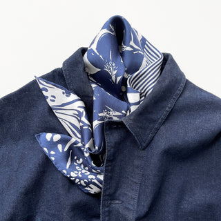 Navy blue silk scarf with white floral and animal print patterns elegantly styled on a denim jacket, showcasing its chic and modern look