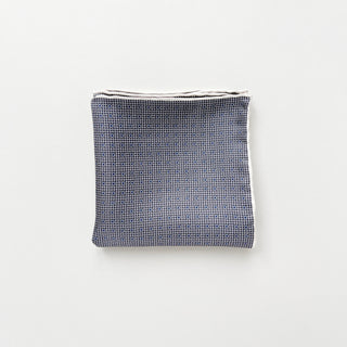 Folded black and white silk scarf with geometric grid and dot pattern, featuring hand-rolled edges and luxurious sheen on white background.