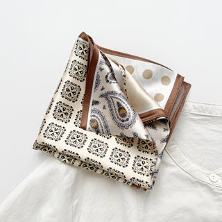Beige silk bandana scarf with mixed paisley and polka dot patterns in earth tones, featuring brown border trim and intricate black designs