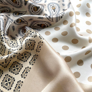Beige silk scarf with mixed patterns featuring paisley design with gold accents, geometric print, and polka dots showing luxurious silky texture