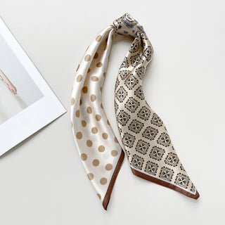 Beige silk scarf with dual-sided design featuring gold polka dots on one side and black paisley pattern on the other, with brown trim edge