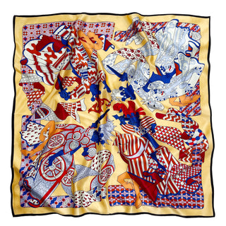 Square silk scarf with light yellow border featuring medieval carnival design in red, blue, and white with intricate decorative patterns and geometric motifs