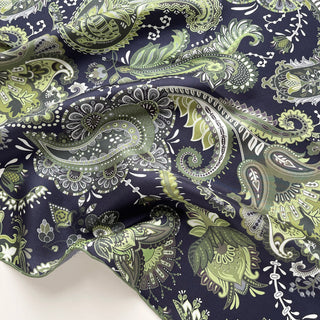 Luxurious silk scarf with intricate paisley pattern in forest green and navy blue, showcasing delicate hand-rolled edges and lustrous twill fabric