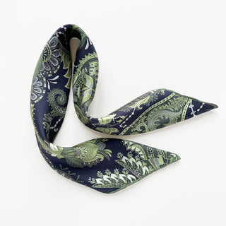 Elegantly draped silk scarf featuring intricate paisley pattern in forest green and navy blue, with hand-rolled edges and lustrous twill finish