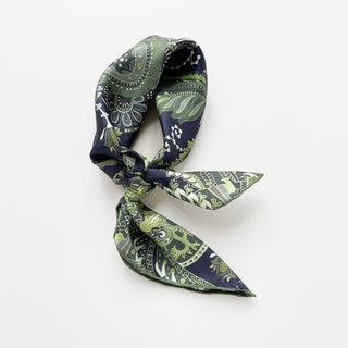 Forest green and navy silk scarf tied in a knot, featuring an intricate paisley pattern with hand-rolled edges against white background