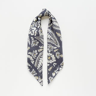 Luxurious ash grey silk scarf with elegant white floral and leaf pattern featuring delicate yellow accents, displayed in a folded triangle shape against white background.