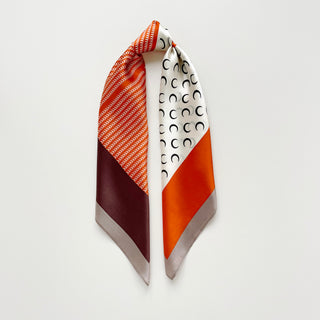 Lunar Peaks silk scarf featuring tangerine orange geometric patterns, white fabric with crescent moon design, burgundy accent, and gray border, elegantly draped