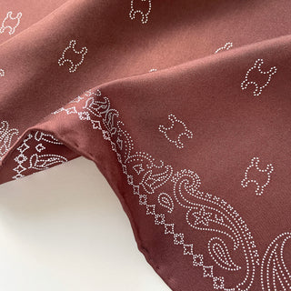 Close-up of Indian Red silk scarf with delicate white dotted paisley pattern, showcasing luxurious twill fabric texture and hand-rolled edge