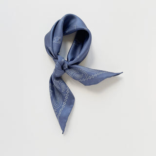 Dusty blue silk neckerchief with white dotted paisley pattern, elegantly knotted to display the hand-rolled edges and luxurious sheen