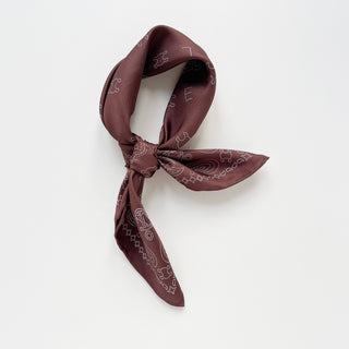 Indian red silk neckerchief with dotted paisley pattern, tied in stylish knot showing hand-rolled edges and Marvel logo detailing