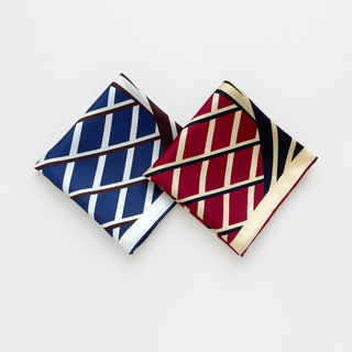 Double-sided silk scarf featuring the Kanagawa wave pattern in two colorways - navy blue with brown trim and vibrant red with black trim, folded to display both sides