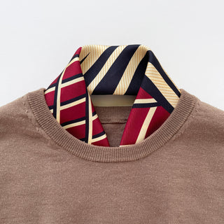 Double-sided silk scarf with red, navy, and cream stripes styled elegantly with a brown sweater, showing the luxurious hand-rolled edges and wave-inspired pattern.