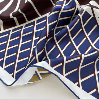 Close-up of double-sided Kanagawa Wave silk scarf showing navy and brown geometric wave pattern with white accents and hand-rolled edges