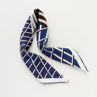 Luxury silk square scarf featuring navy, white, and burgundy geometric pattern with hand-rolled edges, shown folded against white background
