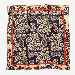 Luxury square silk scarf with navy and beige paisley pattern, orange border trim, and hand-rolled edges, displayed flat showing intricate design