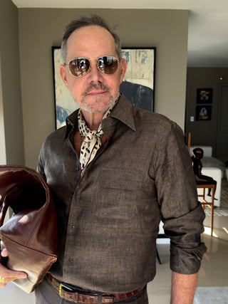 Men’s geometric silk scarf in chocolate bar print styled with a dark brown shirt and trousers, accessorized with vintage sunglasses and leather clutch.