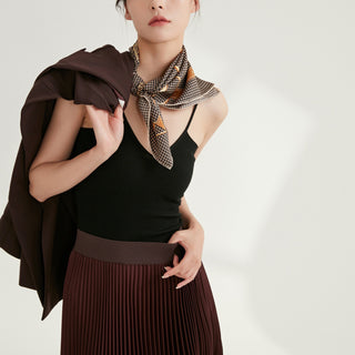 Black and beige houndstooth silk scarf styled as a neck accessory with a black top, brown pleated skirt, and matching jacket