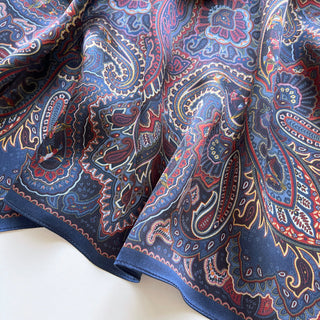 Navy blue silk neckerchief with intricate burgundy and gold paisley pattern, featuring shimmering fabric texture and decorative border design