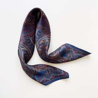 Silky navy blue men's neckerchief with intricate burgundy paisley pattern, elegantly draped to showcase its lustrous finish and bohemian design.