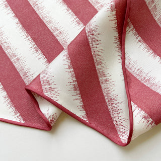 Luxury silk scarf in grapefruit pink and cream stripes with soft-edged pattern detail, showcasing hand-rolled edges and matte sand-washed finish