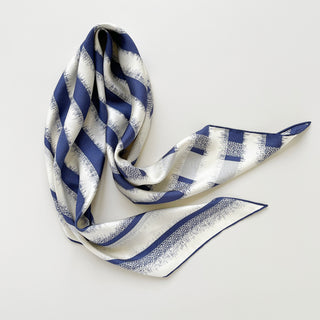 Luxurious triangle silk scarf with blue and white striped pattern, showcasing hand-rolled edges and soft sand-washed finish, elegantly draped on white background