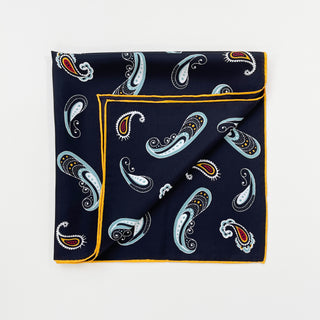 Navy blue silk scarf with decorative paisley pattern in light blue, gold, and red accents, featuring elegant hand-rolled yellow border
