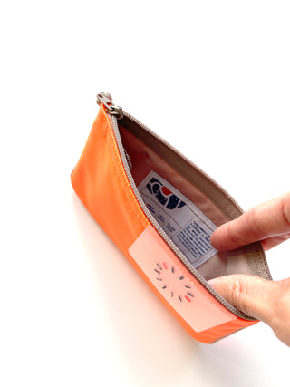 Bright orange recycled RPET zipper wallet shown open, revealing light interior with product tag and traditional Chinese button detail on front