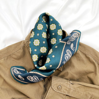 Pacific blue silk neckerchief with gold medallion pattern and paisley border, elegantly styled on a tan shirt collar