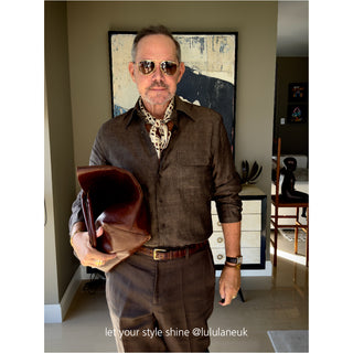 Men’s geometric silk scarf in chocolate bar print styled with a dark brown shirt and trousers, accessorized with vintage sunglasses and leather clutch.