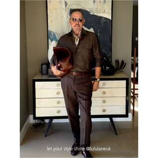 Men’s geometric silk scarf in chocolate bar print styled with a dark brown shirt and trousers, accessorized with vintage sunglasses and leather clutch.
