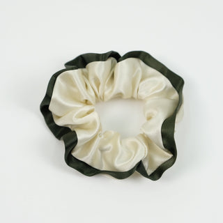 Handmade silk scrunchie with cream center and dark green trim, showcasing the ruffled texture and lustrous fabric against white background.
