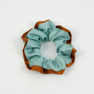 Luxurious silk scrunchie featuring seafoam blue fabric with copper-colored edge trim, showcasing the ruffled, handmade design against white background