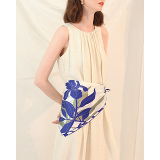 Woman wearing a blue iris patterned silk scarf in a cream dress
