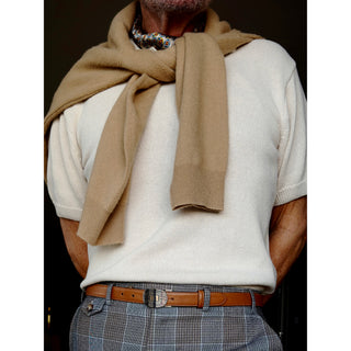 Man wearing a cream knitted polo shirt styled with a geometric print silk neckerchief scarf in warm brown and blue tones showcasing a refined stylish look.