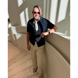 Man wearing an ivory paisley pattern silk bandana square by LuluLane in dark blazer and white trousers with sunglasses showcasing a refined, smart causal look.