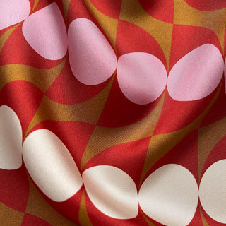 Close-up of geometric mid-century silk scarf by LuluLane with Bauhaus-inspired design in red, pink and brown tones.