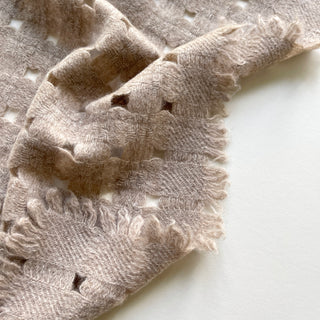 Close-up of a beige 100% cashmere long scarf with lace-inspired knitted jacquard.