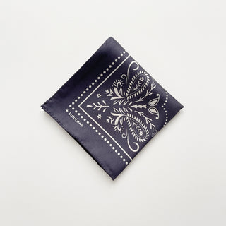 Folded charcoal grey silk bandana scarf, 65cm square with modern paisley print and hand-rolled hems by LuluLane.