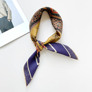 Indigo Royal Vintage Bloom silk scarf elegantly knotted, featuring intricate floral and geometric patterns in gold, orange, and red against an indigo background