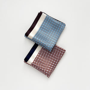 two silk scarves with featuring circle print in red and sky blue, folded as squares
