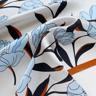 Close-up of a women’s silk bandana scarf 53cm with tulip floral print, double-sided satin square with burnt orange border by LuluLane