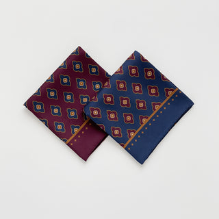 Two folded men’s paisley silk scarves 65cm in navy blue and burgundy, double-sided silk twill squares with hand-rolled hems by LuluLane