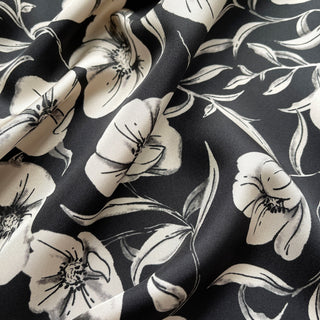 Close-up of a women’s 65cm silk square scarf with off white poppy blossom floral print in black background